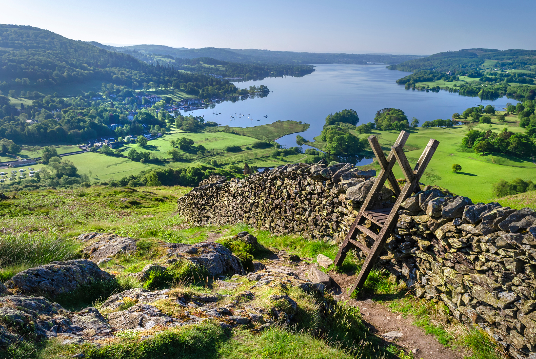 Scenic view of the Lake District, cobbled wall and hiking style overlooking a lake on a sunny day